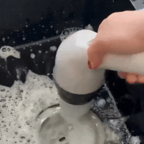 Lavabo del baño con espuma durante la limpieza con la mopa eléctrica giratoria